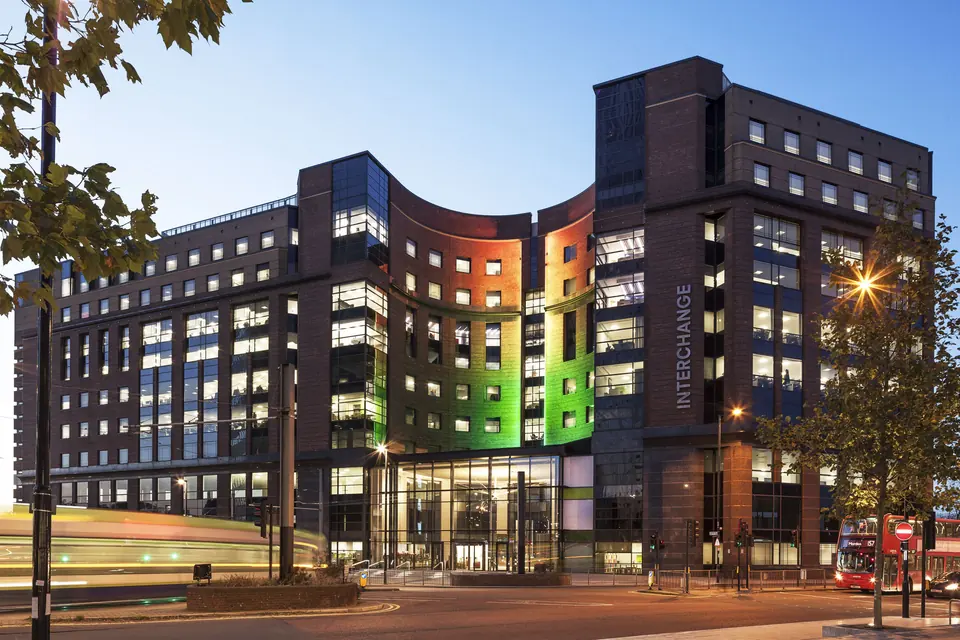 The Interchange building lit up at dusk on Station Road