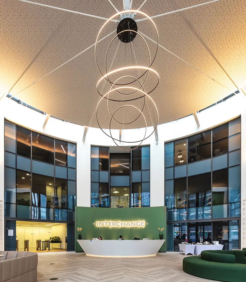 Triple-height reception with green feature desk and suspended ring light